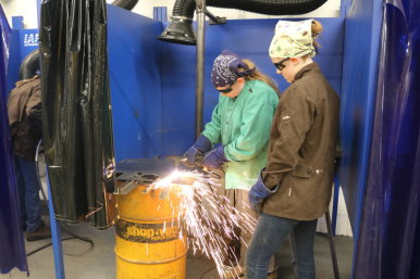 Student uses a plasma cutter at Rosie's Girls Weld as sparks fly