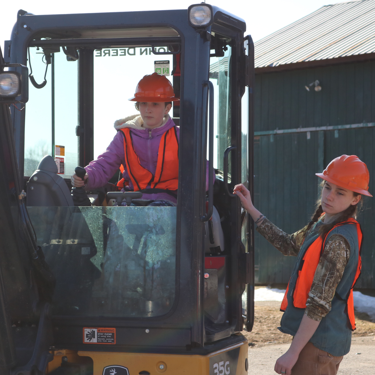 At Career Challenge Day a middle school girls uses an excavator with help from a tech center student