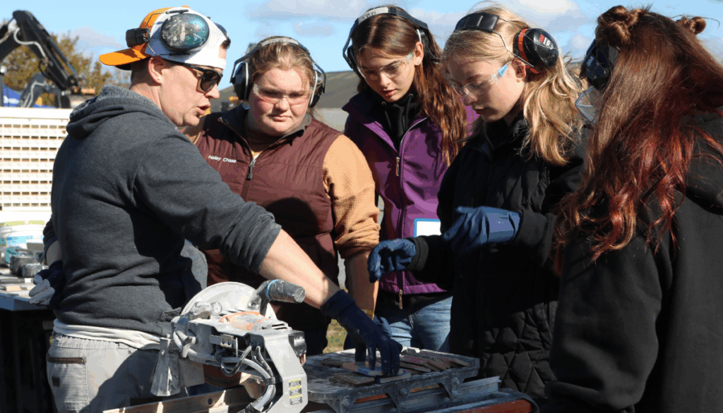 High school students cut tile using a saw at Women Can Do
