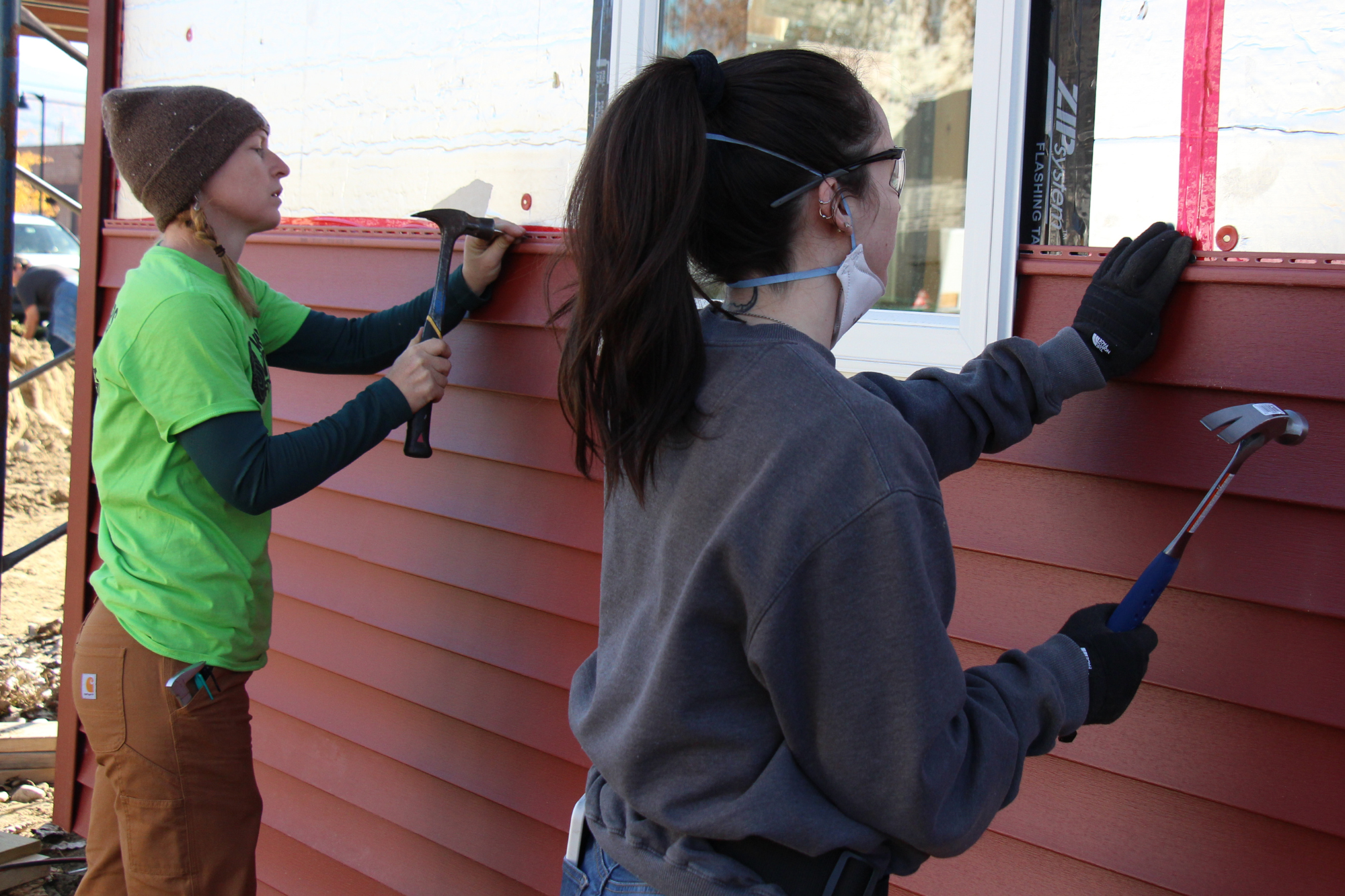 Woman uses a hammer to install siding during the Trailblazers trades training program by Vermont Works for Women