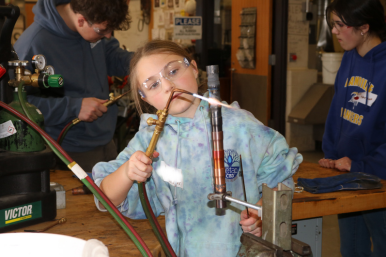 A middle school student solders copper wire at Career Challenge Day