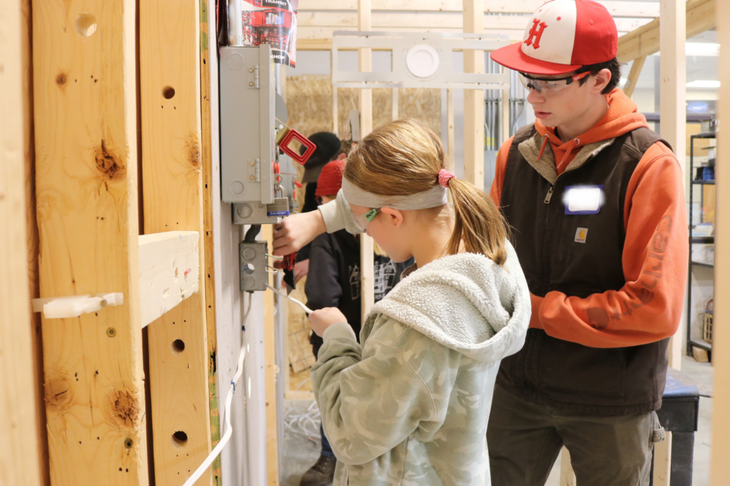 A middle school student wires an electrical box at Career Challenge Day