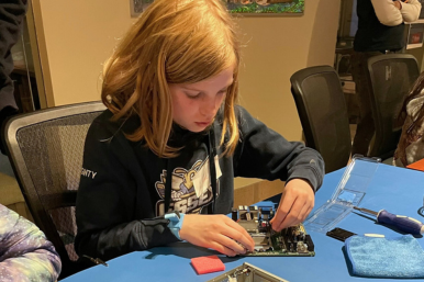 Camper works on a computer motherboard at Rosie's Girls TECH.