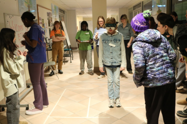 Rosie's Girls TECH camper navigates through a maze blindfolded by listening to their teammates, without the “disrupters” confusing them.