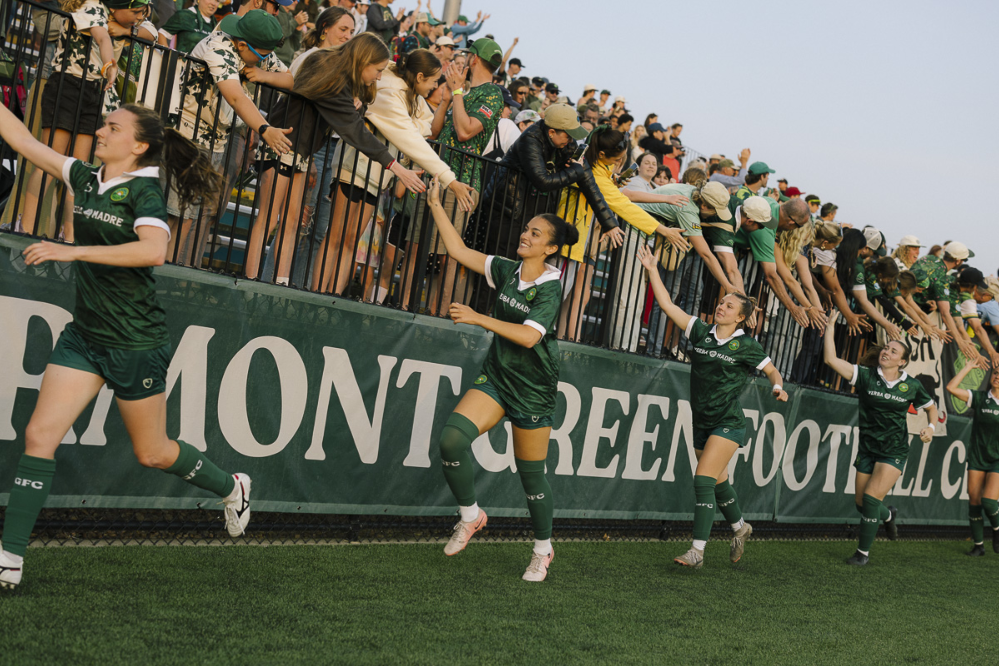 Vermont Green women's team high fives fans after a winning game
