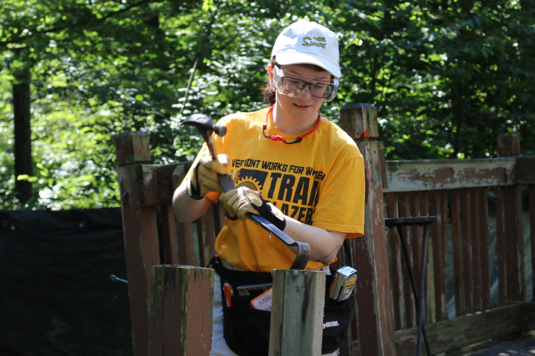 Trailblazer uses a hammer and crow bar to demolish a rotten deck.