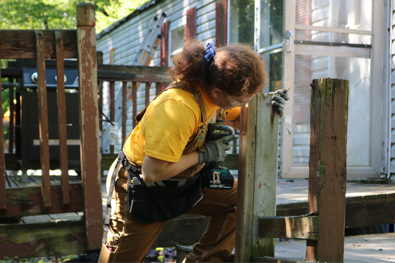 A Trailblazer uses a drill to remove old screws from a rotting staircase
