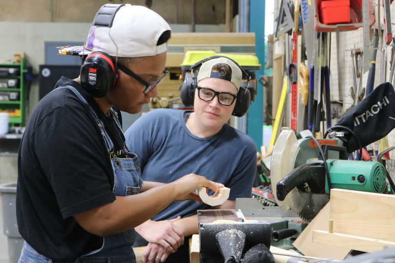 A LIFT participant uses a belt sander during carpentry instruction