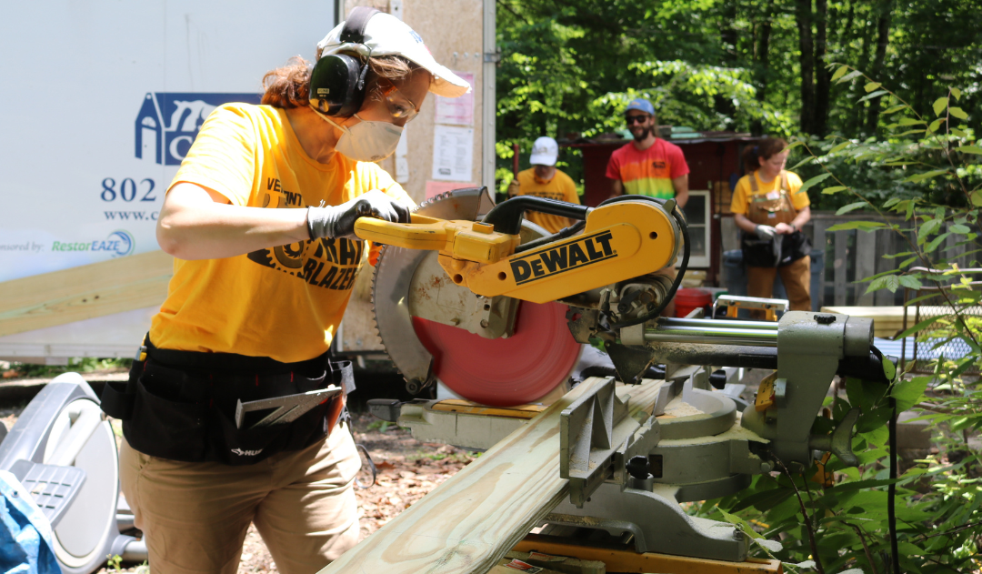 A Trailblazers participant uses a saw on a COVER Home Repair build site