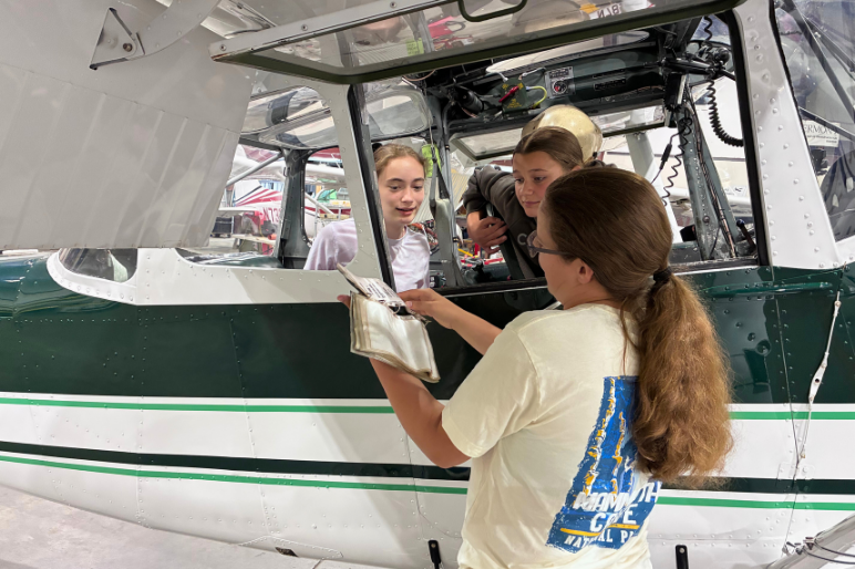 Campers at Rosie's Girls Aviation sit in a small plane