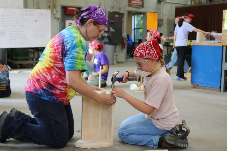 A VWW staff member helps a camper build a wooden box.