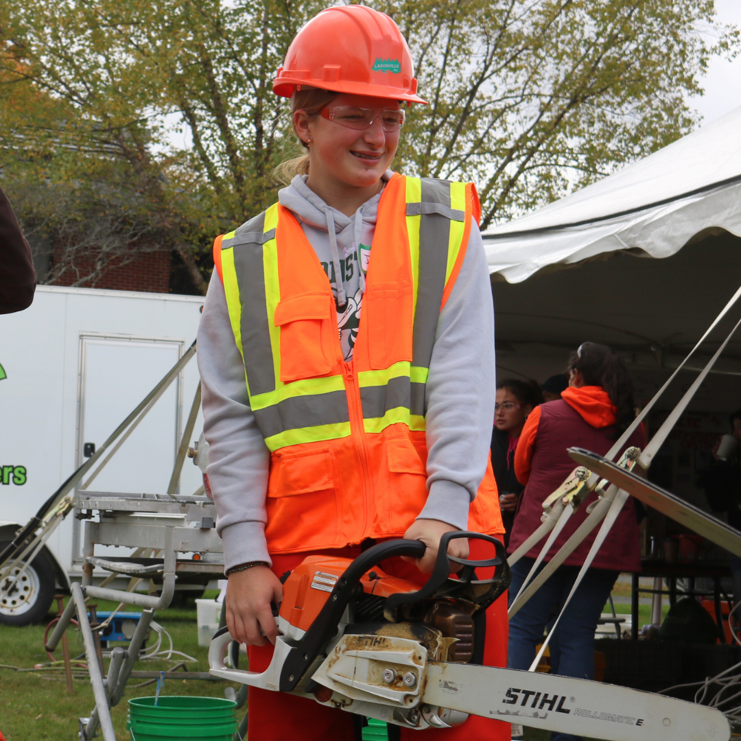 A student holds a chainsaw at Women Can Do