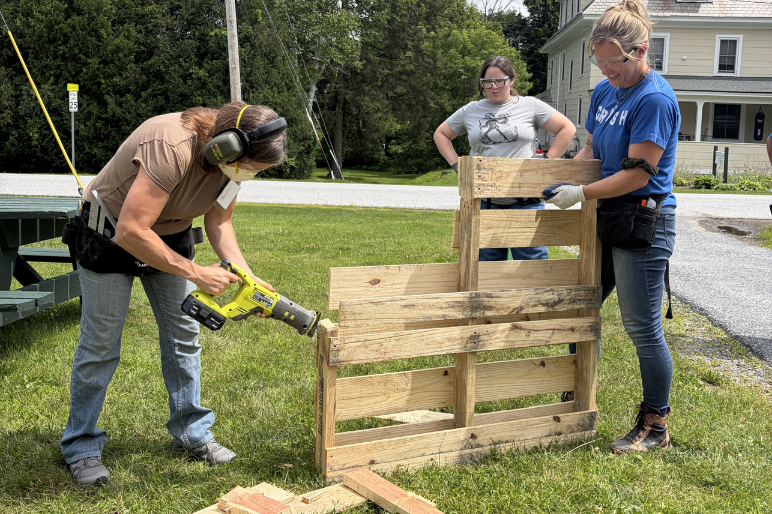 Trailblazers participants practice using power tools by breaking apart wooden pallets